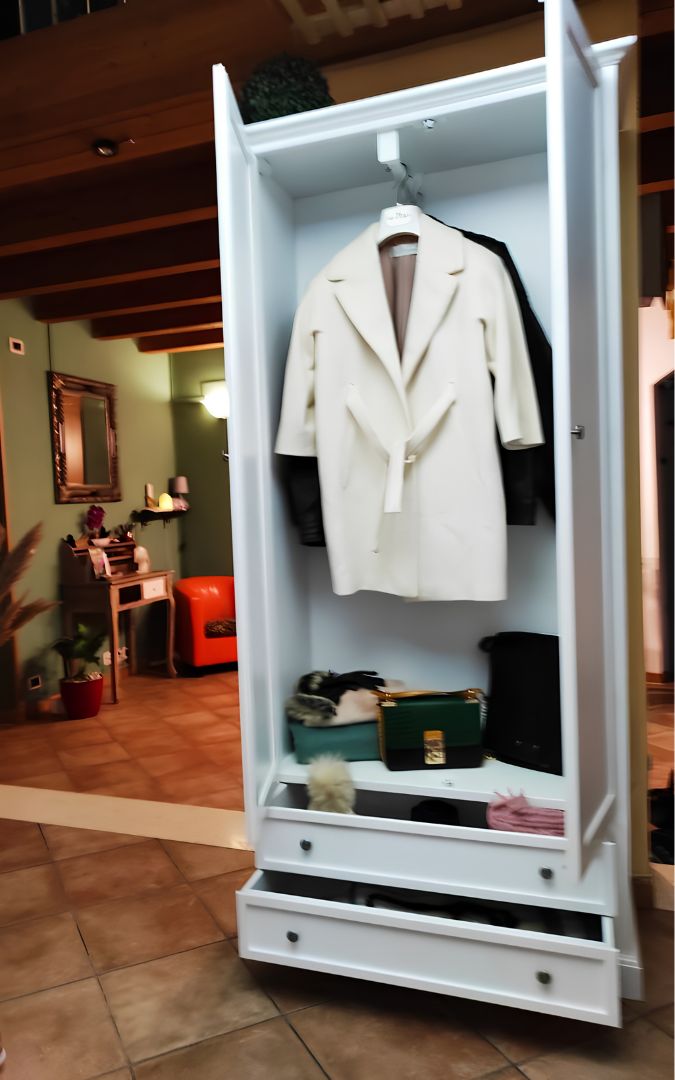 Interno dell'armadio in legno bianco stile Arte Povera, mostrato con abiti appesi e cassetti inferiori aperti.
