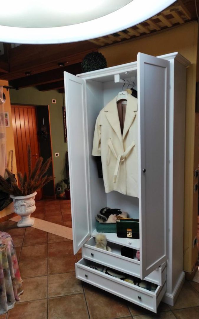 Dettaglio interno dell'armadio bianco, con cappotto appeso e accessori riposti, stile classico.