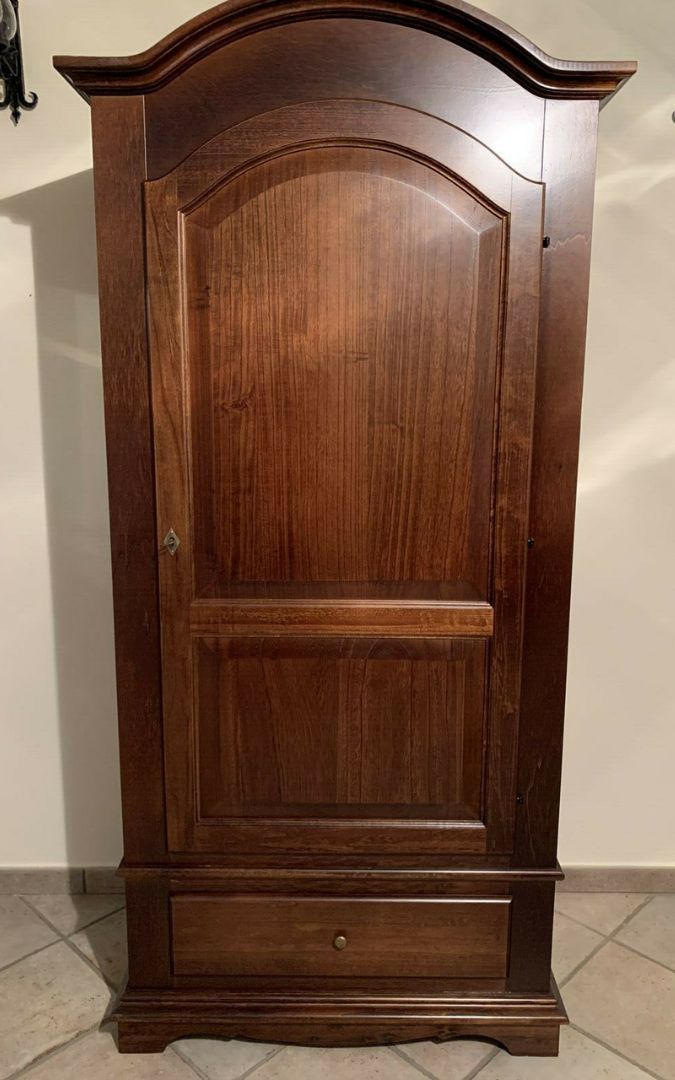 Armadio a una porta in legno noce scuro aperto, posizionato in un ambiente domestico.