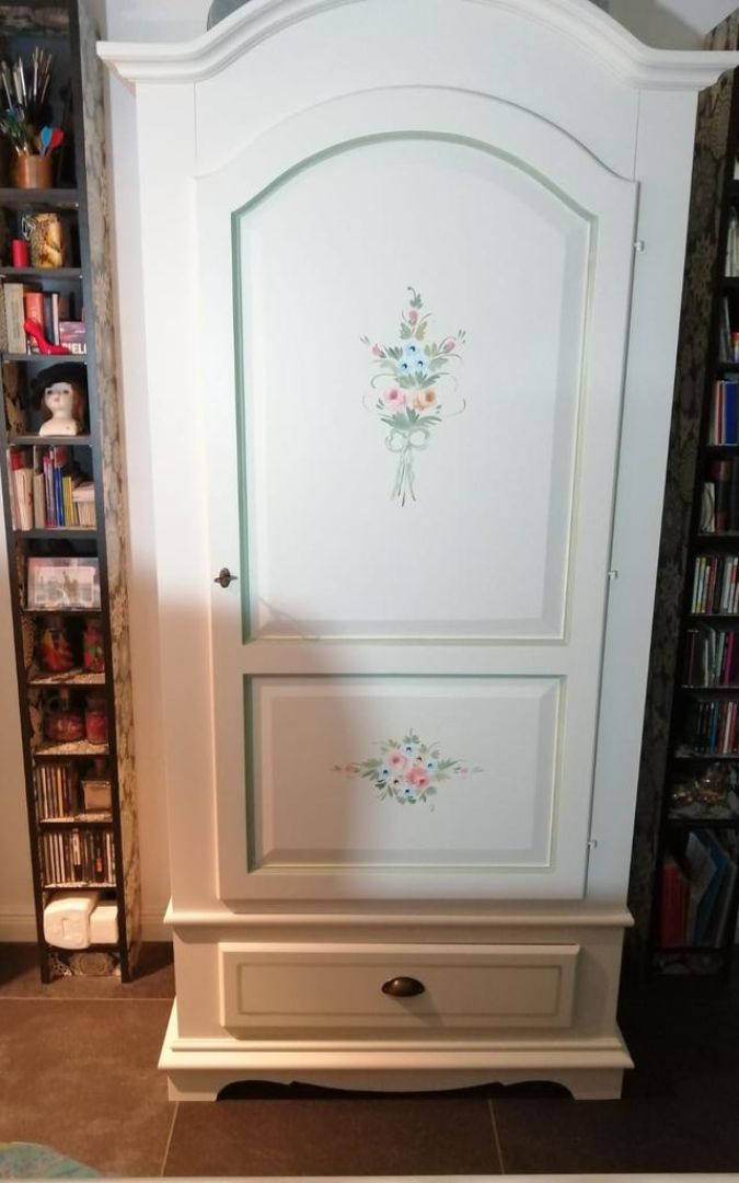Armadio in legno bianco con decori floreali, vista frontale in interno.