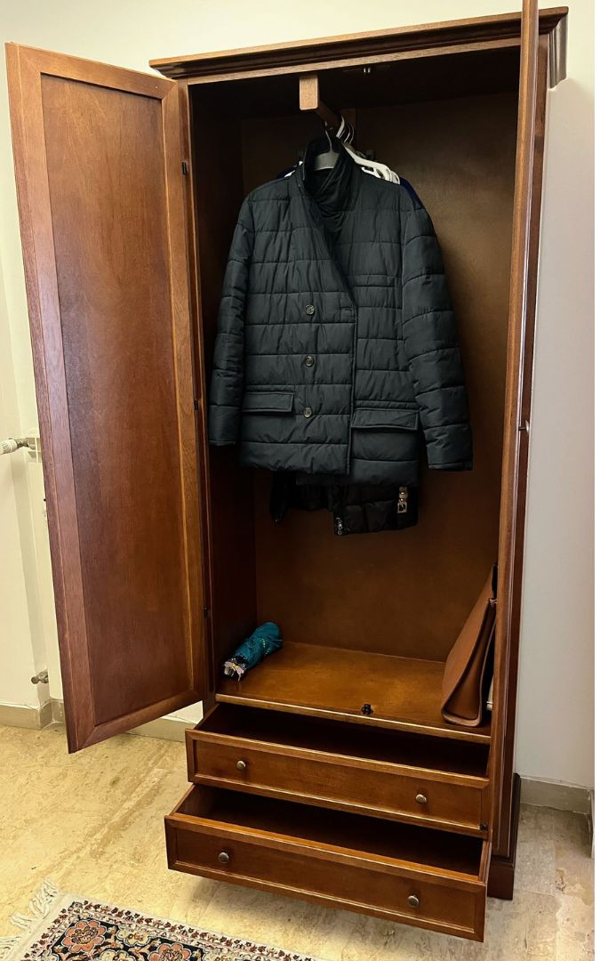 Armadio a due ante in legno noce scuro, con finiture classiche e cassetti, in una stanza da letto.
