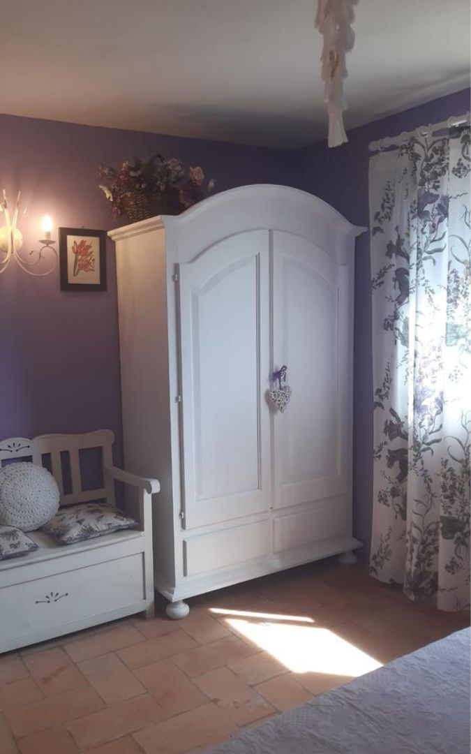 Armadio bianco opaco in stile Arte Povera inserito in una camera con decorazioni, con cuore decorativo appeso.