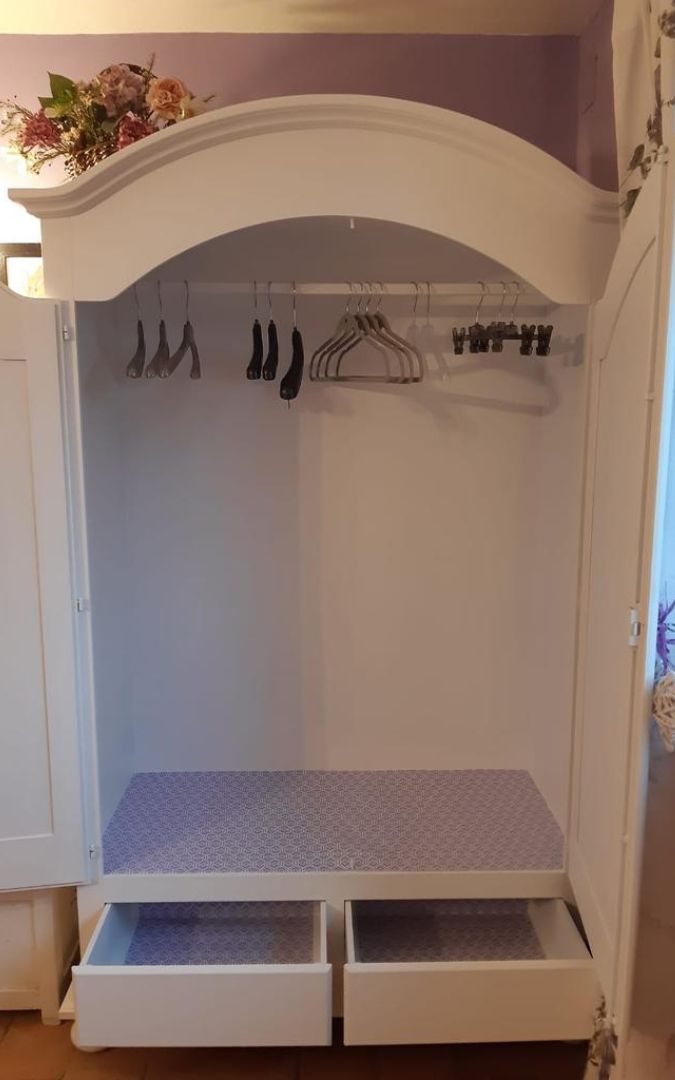 Interno di armadio in legno bianco con cassetti foderati e asta appendiabiti, design funzionale.