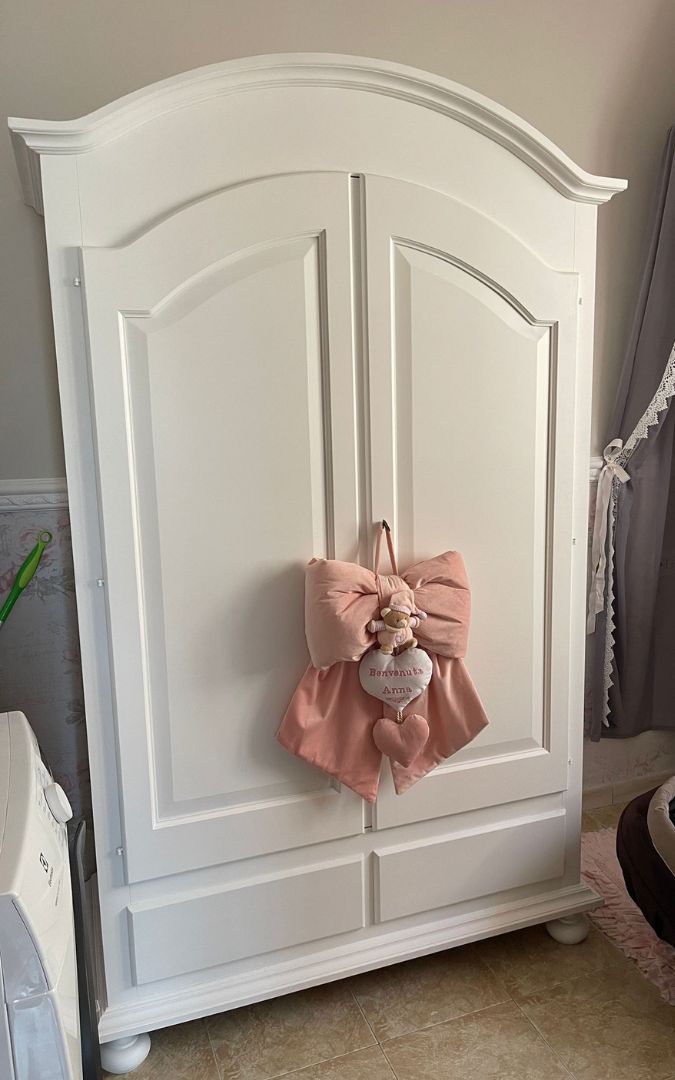 Armadio bianco stile Arte Povera posizionato in un ambiente accogliente, vista frontale completa.