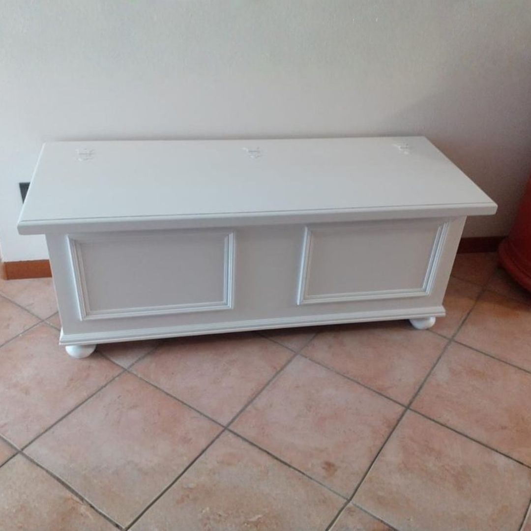 Cassapanca in legno bianco opaco posizionata su pavimento in cotto, design elegante Arte Povera.