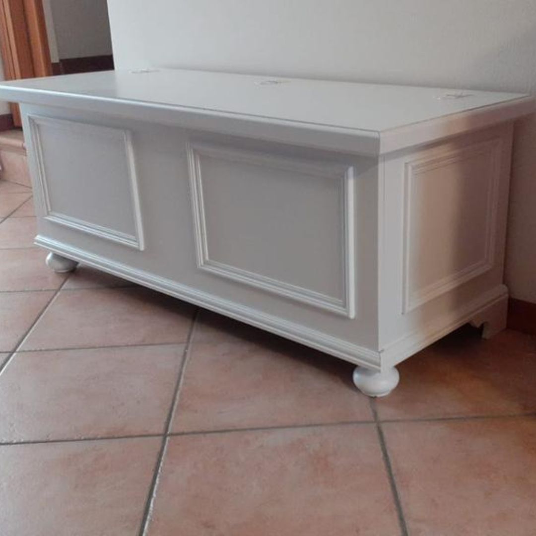 Cassapanca in legno bianco opaco in stile classico, vista di tre quarti, evidenziando il design pulito e i piedi a cipolla.