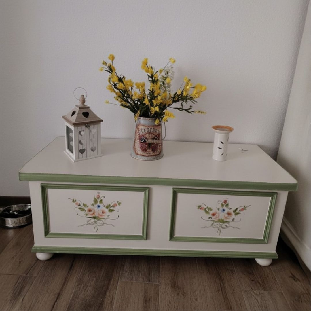 Cassapanca in legno con decori floreali e lanterna poggiata sopra