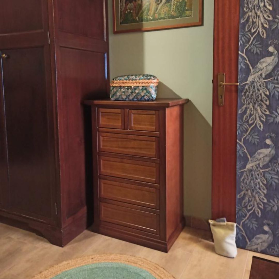 Cassettiera in legno noce scuro con cassetti, inserita in un ambiente classico vicino a una scrivania.