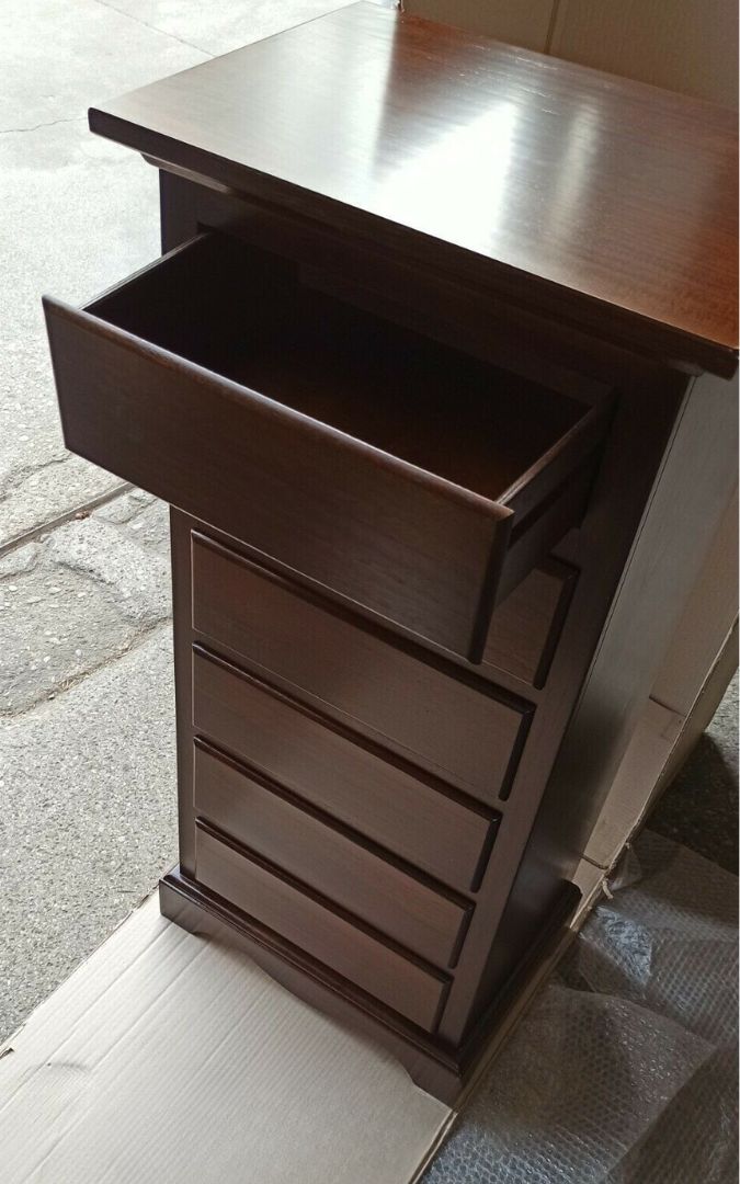 Dettaglio di una cassettiera in legno noce scuro a sei cassetti con pomelli metallici.
