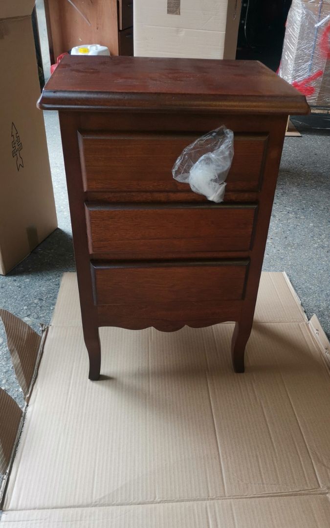 Dettaglio frontale di un comodino in legno a 3 cassetti, finitura noce scuro e design elegante