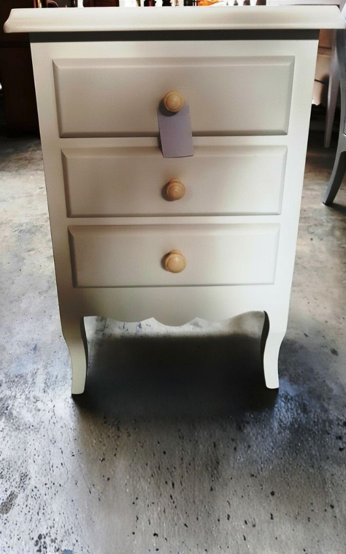Comodino bianco a 3 cassetti con lampada da tavolo, esempio di arredamento per camera in stile classico.