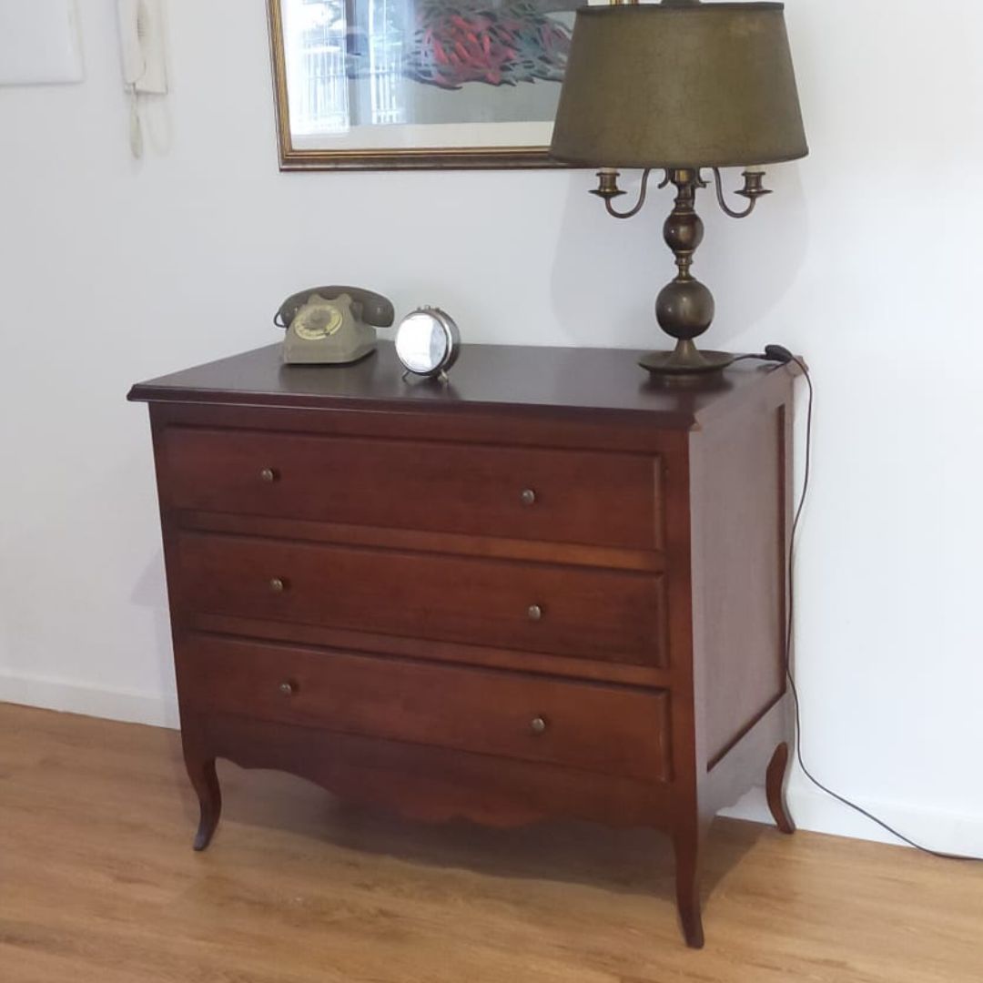 Comò in legno finitura noce scuro con lampada vintage e telefono d'epoca.
