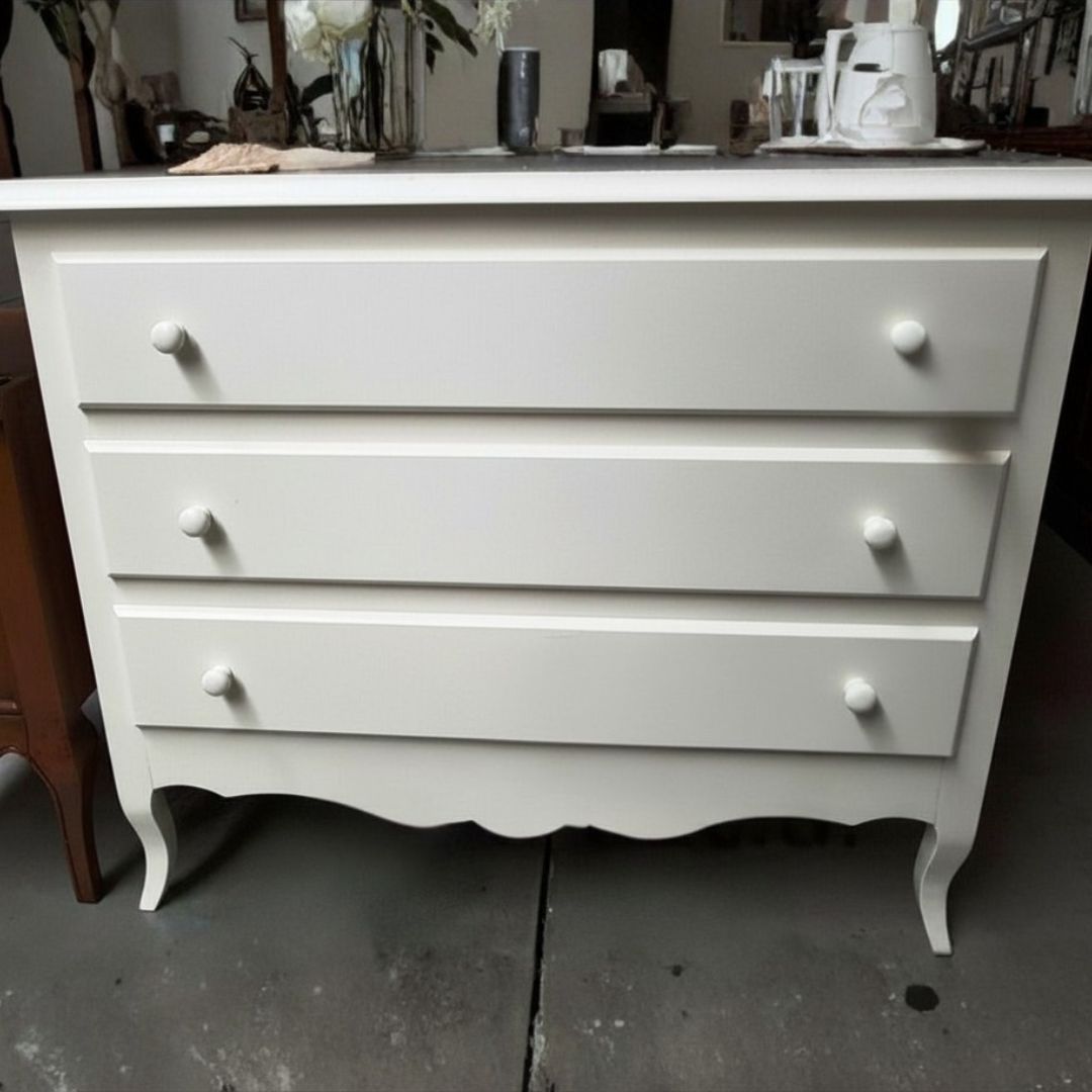 Comò in legno bianco posizionato in una stanza, decorato con candele e complementi d'arredo.