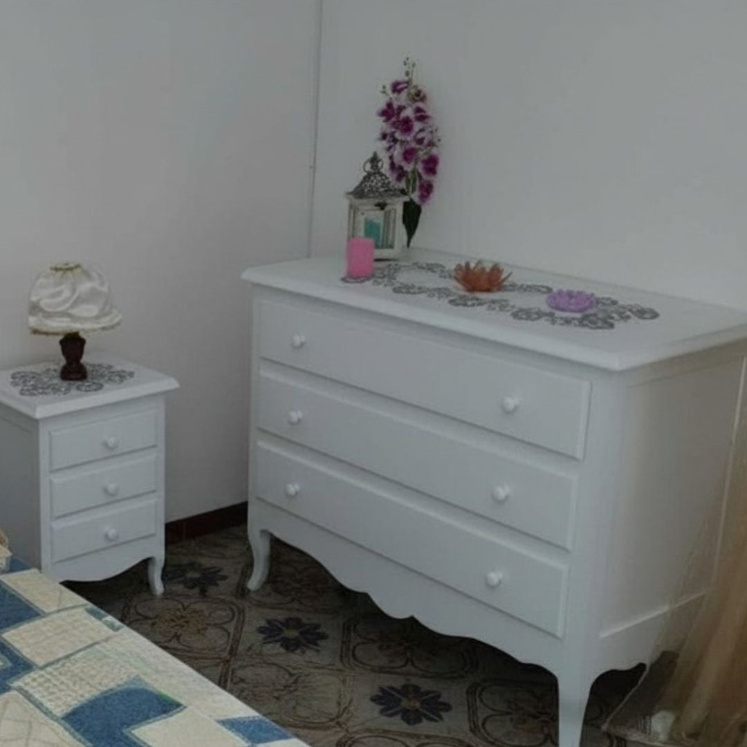 Dettaglio di comò bianco opaco con tre cassetti in un ambiente luminoso, stile raffinato Arte Povera.
