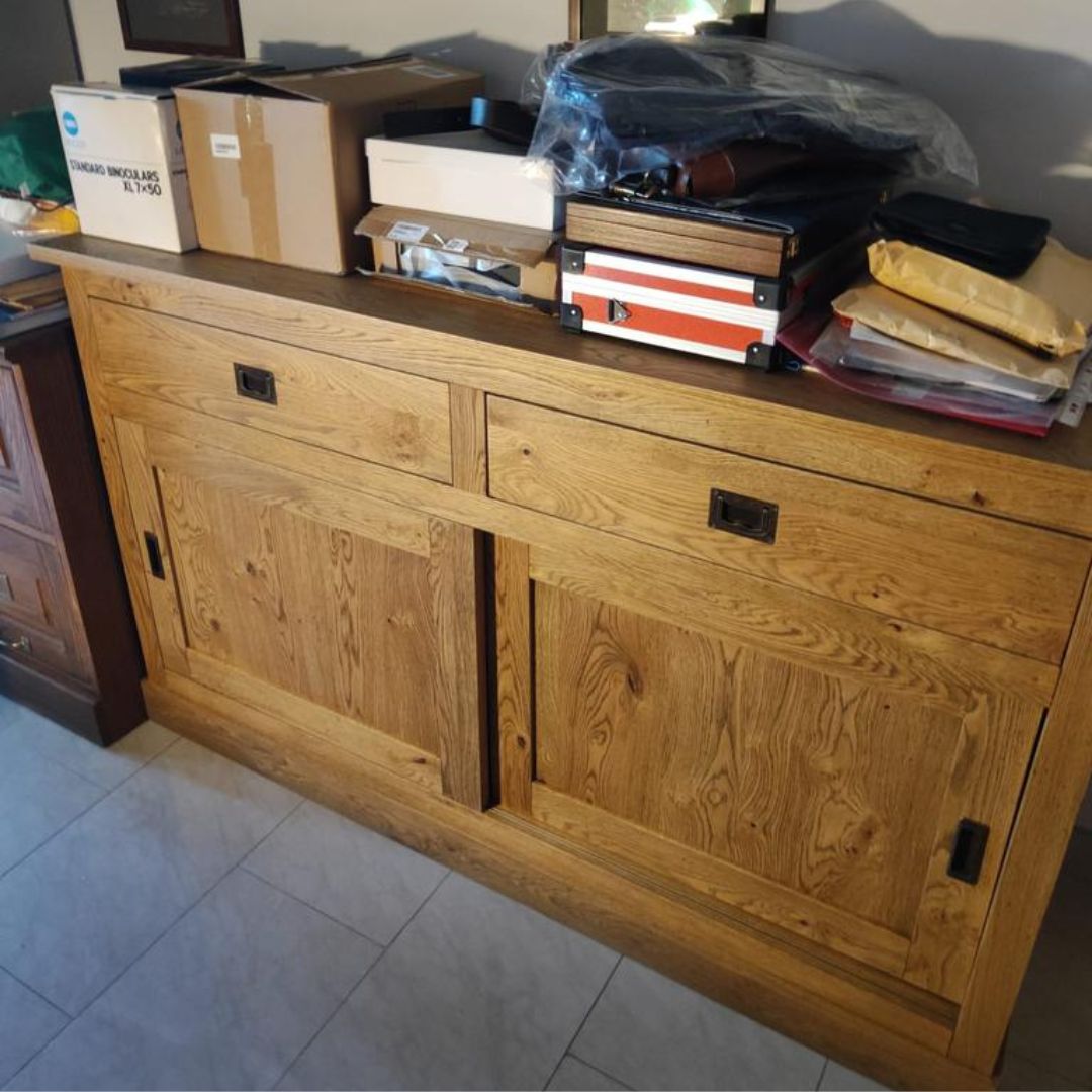 Mobile buffet in legno rovere con ante scorrevoli e cassetti, posizionato contro una parete colorata.