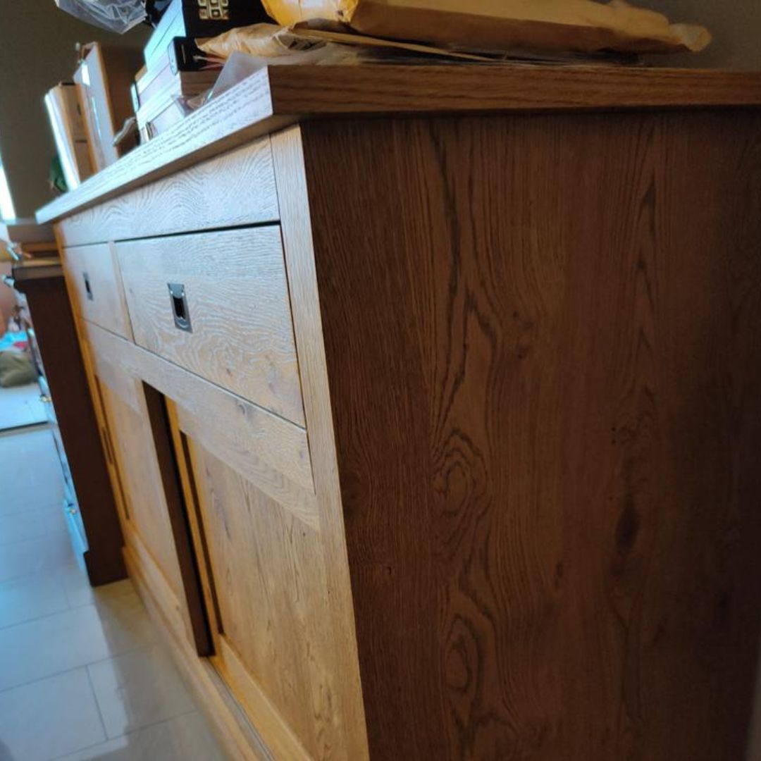 Credenza in legno rovere naturale con cassetto estratto, vista frontale su sfondo arancione.