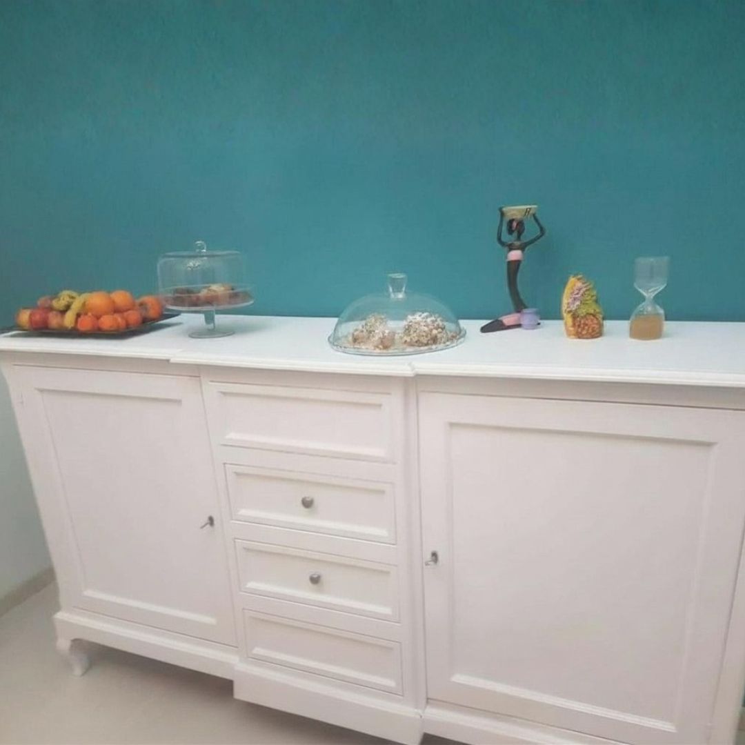 Dettaglio interno di una credenza in legno bianco, che mostra il ripiano centrale e la struttura dei cassetti laterali.