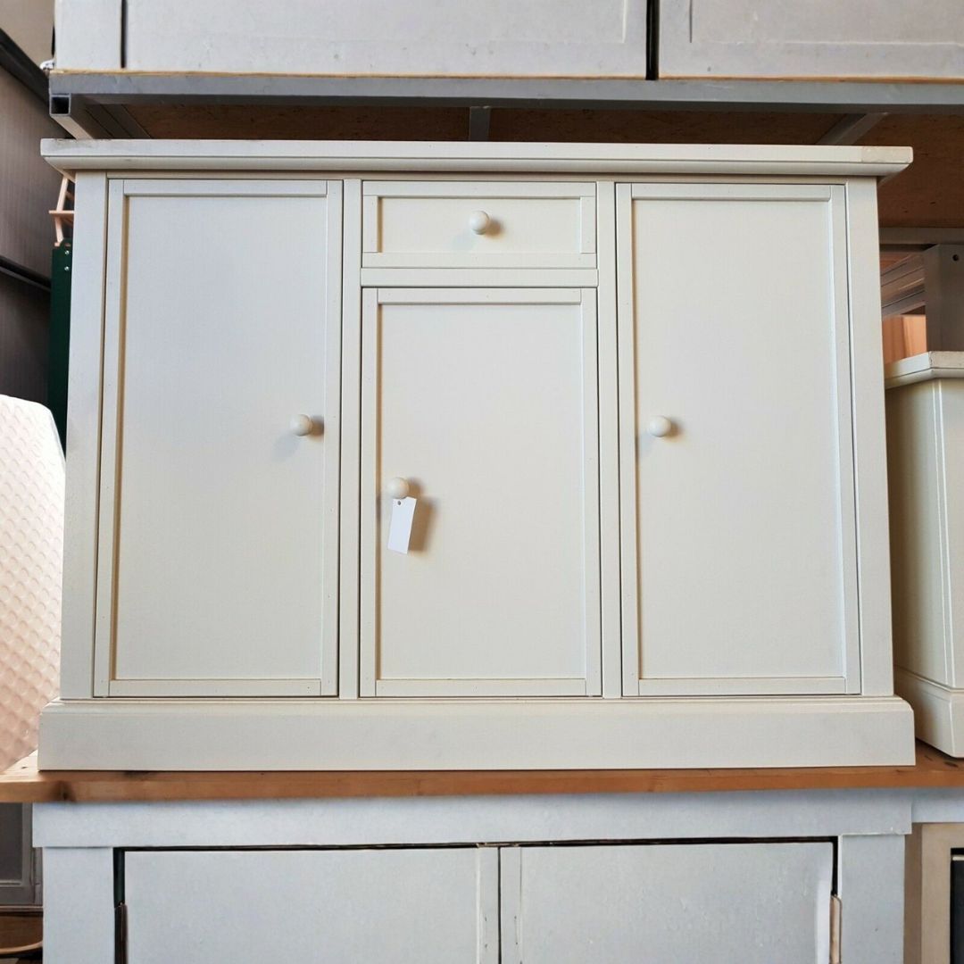 Madia in legno bianco opaco in stile classico, posizionata in un ambiente domestico con decorazioni rustiche sopra il piano.