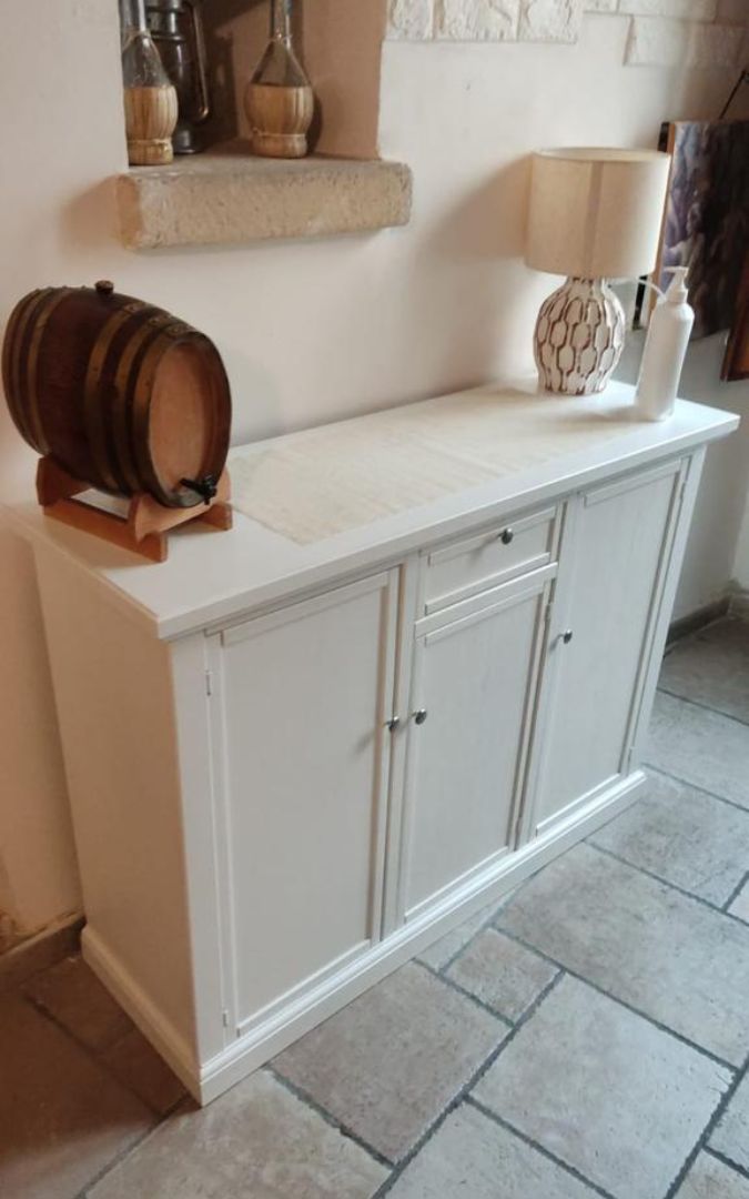 Mobile credenza bianco in stile Arte Povera utilizzato come supporto TV in un ambiente classico.