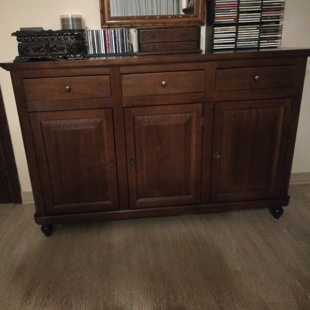 Vista frontale di una credenza in legno noce scuro con tre cassetti e tre ante chiuse.