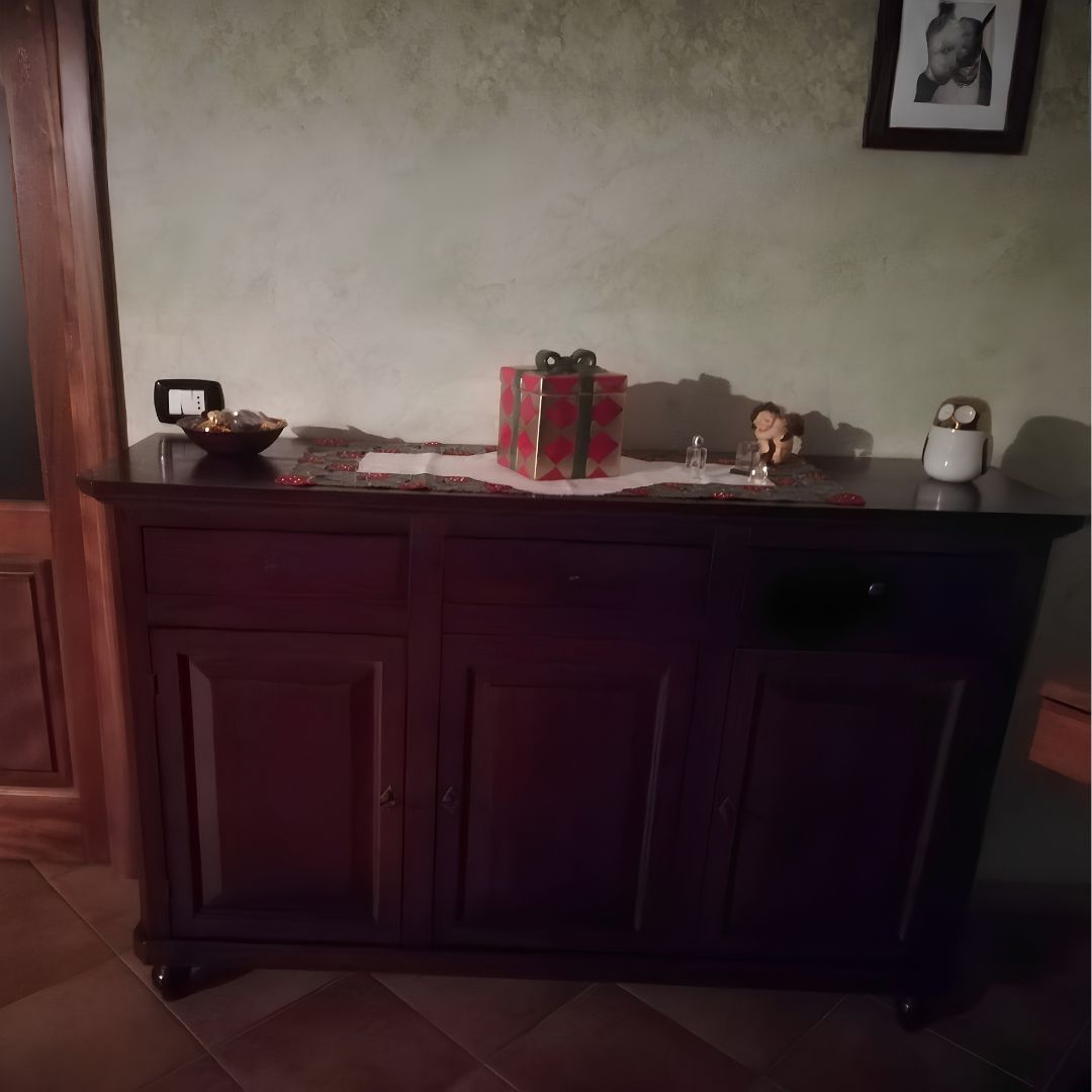 Credenza in legno scuro posizionata contro una parete, arredata con oggetti decorativi sopra il piano.