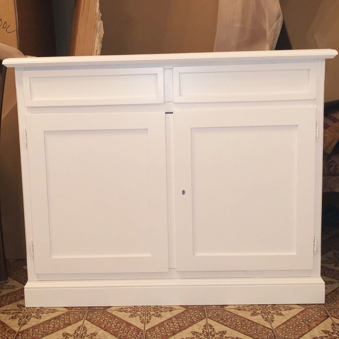 Credenza in legno bianco opaco con due ante e due cassetti, stile Arte Povera, vista frontale.