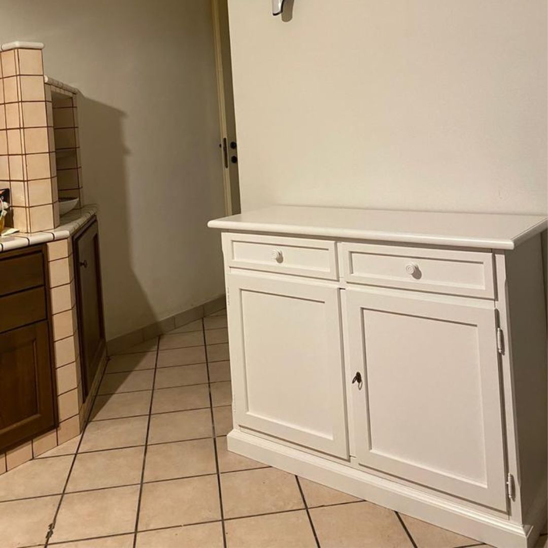 Credenza in legno bianco opaco posizionata in un corridoio, stile classico e funzionale.