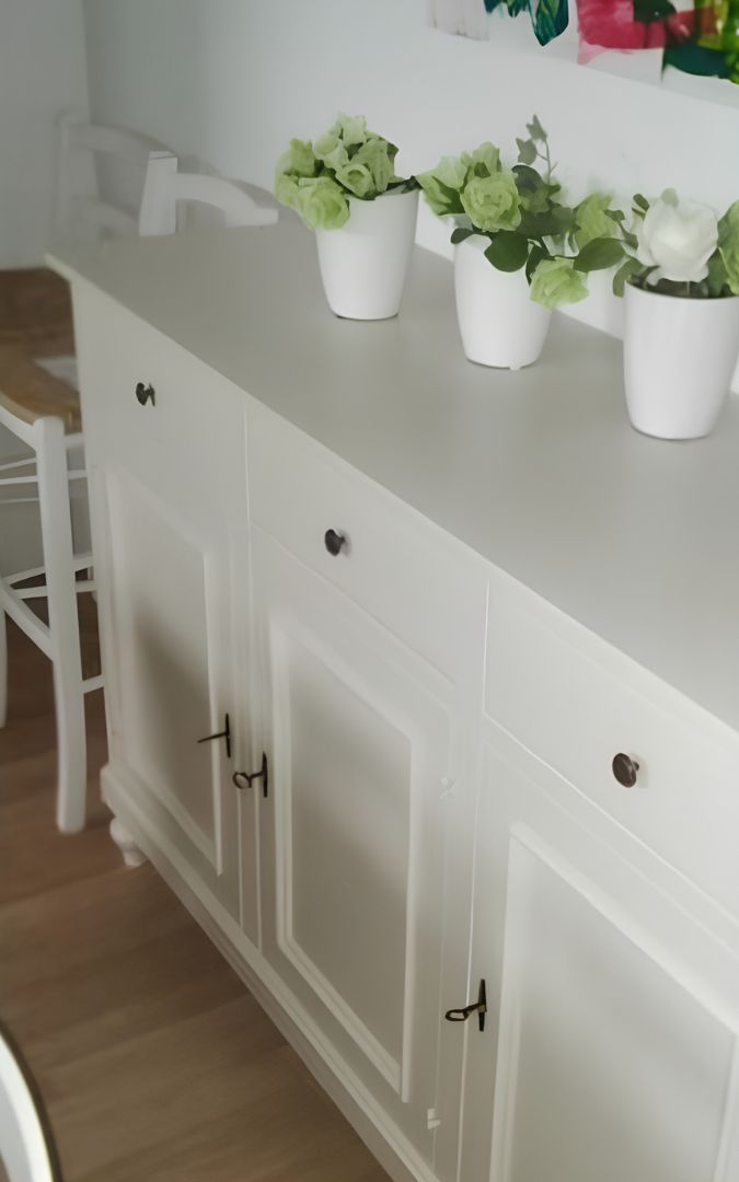 Dettaglio interno dei ripiani di una credenza in legno bianco con ante aperti.
