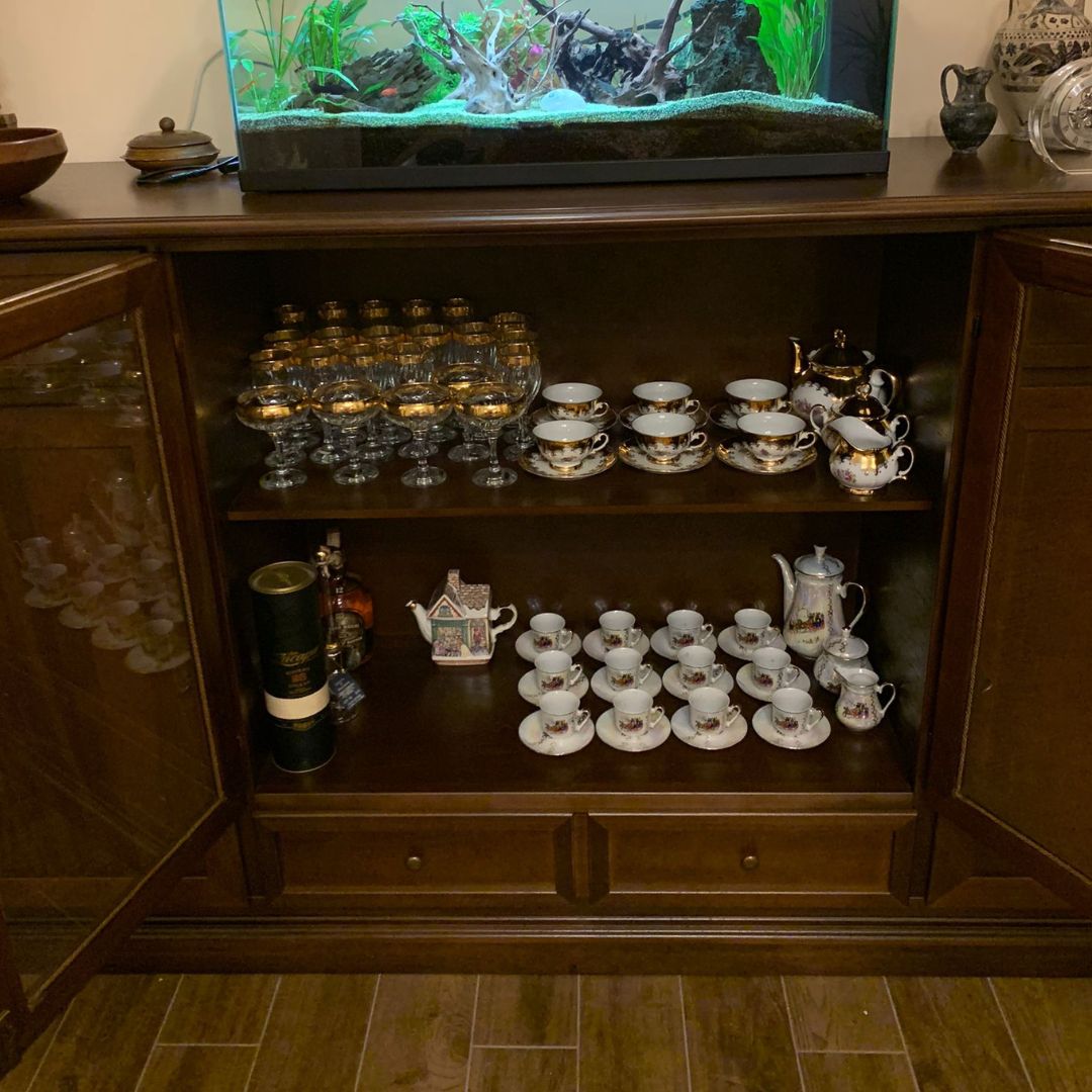 Interno vetrina credenza stile arte povera, ripiani con servizio da tè, tazzine e bicchieri eleganti