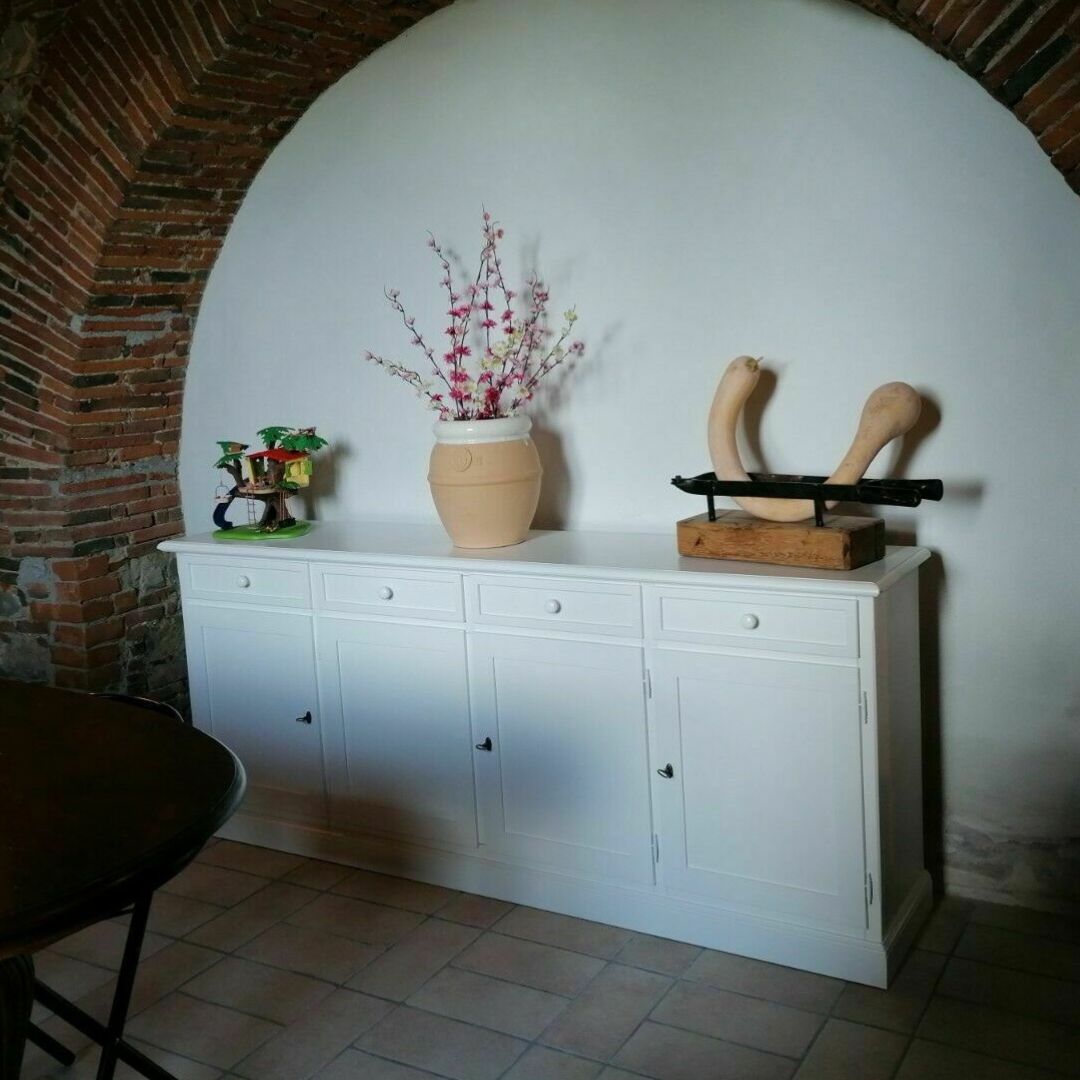 Credenza bianca opaca 4 ante con decorazioni in una nicchia in pietra.