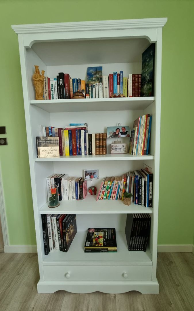 Elegante libreria bianca con struttura in legno, ripiani spaziosi e cassetto, in un ambiente domestico.