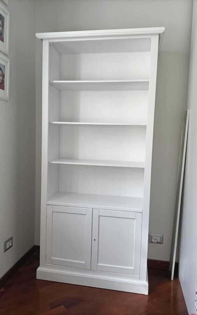 Vetrina alta in legno bianco opaco con ante a vetro e base chiusa, stile Arte Povera.