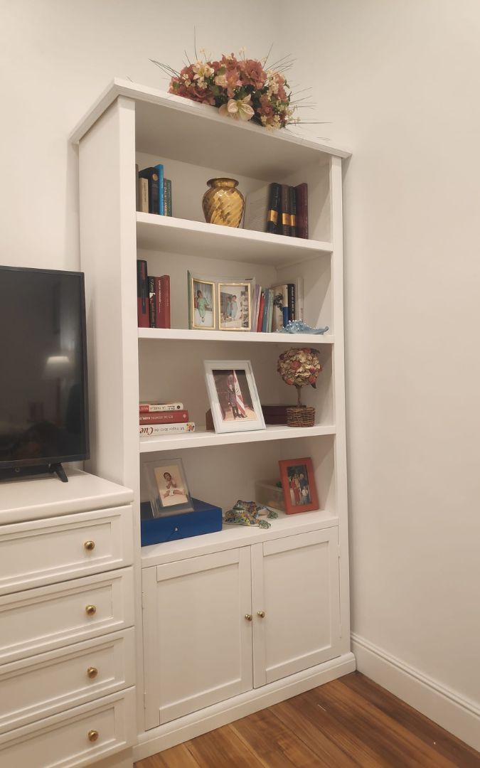 Dettaglio di una libreria in legno bianco stile Arte Povera arredata con libri e oggetti decorativi, vista frontale.