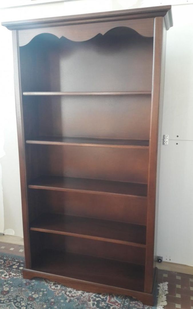 Dettaglio superiore di una libreria in legno noce scuro con finiture classiche sagomate.