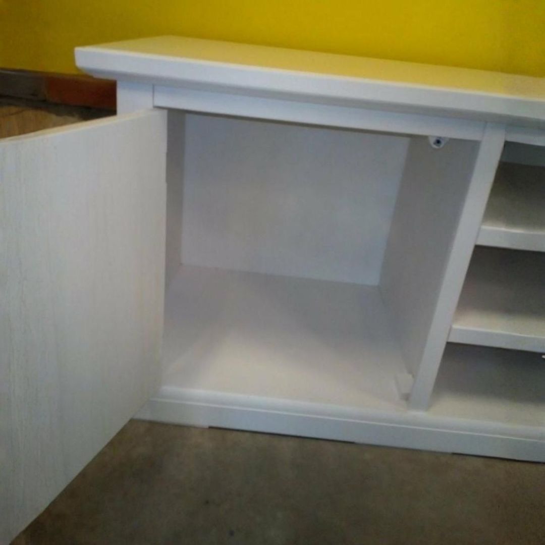 Mobile basso porta TV in legno bianco con vani a giorno per dispositivi elettronici e ante laterali.
