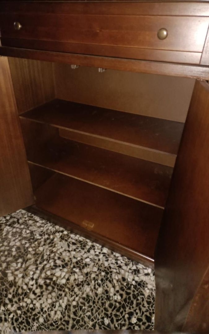 Interno di un mobile scarpiera stile arte povera in legno noce scuro con ripiani a vista.