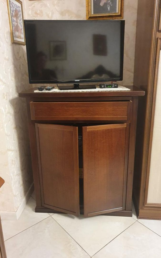 Vista frontale di una scarpiera in legno noce scuro, design essenziale stile arte povera.