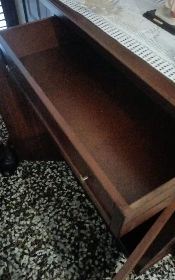 Dettaglio del cassetto superiore aperto di una scarpiera in legno noce scuro.