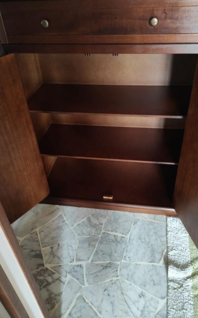 Scarpiera in legno noce scuro posizionata in un angolo della casa, stile classico arte povera.