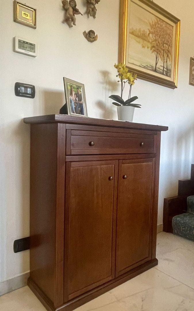 Mobile multiuso in legno noce scuro con TV posizionata sul ripiano superiore.