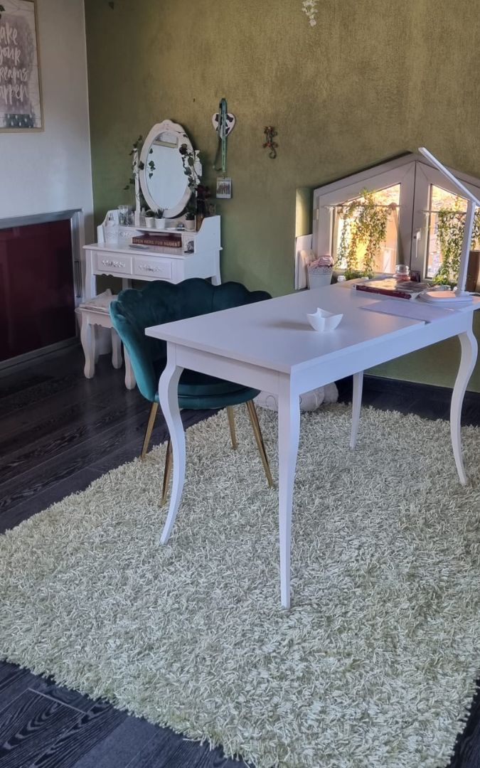 Scrivania in legno bianco opaco stile classico con 2 cassetti, posizionata in un ambiente living con sedia moderna.