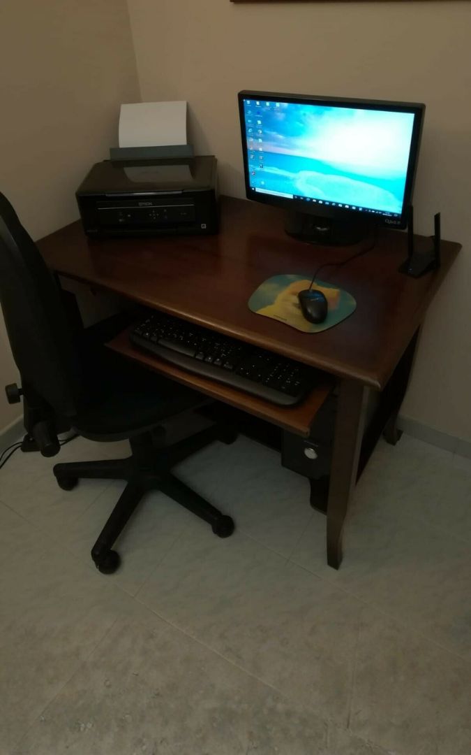 Postazione di lavoro con scrivania in legno scuro, sedia, monitor PC, mouse e stampante Epson.
