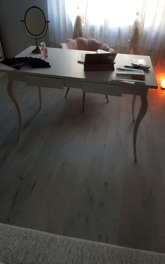 Scrivania bianca con cassetti usata come postazione studio, design elegante e gambe curve.