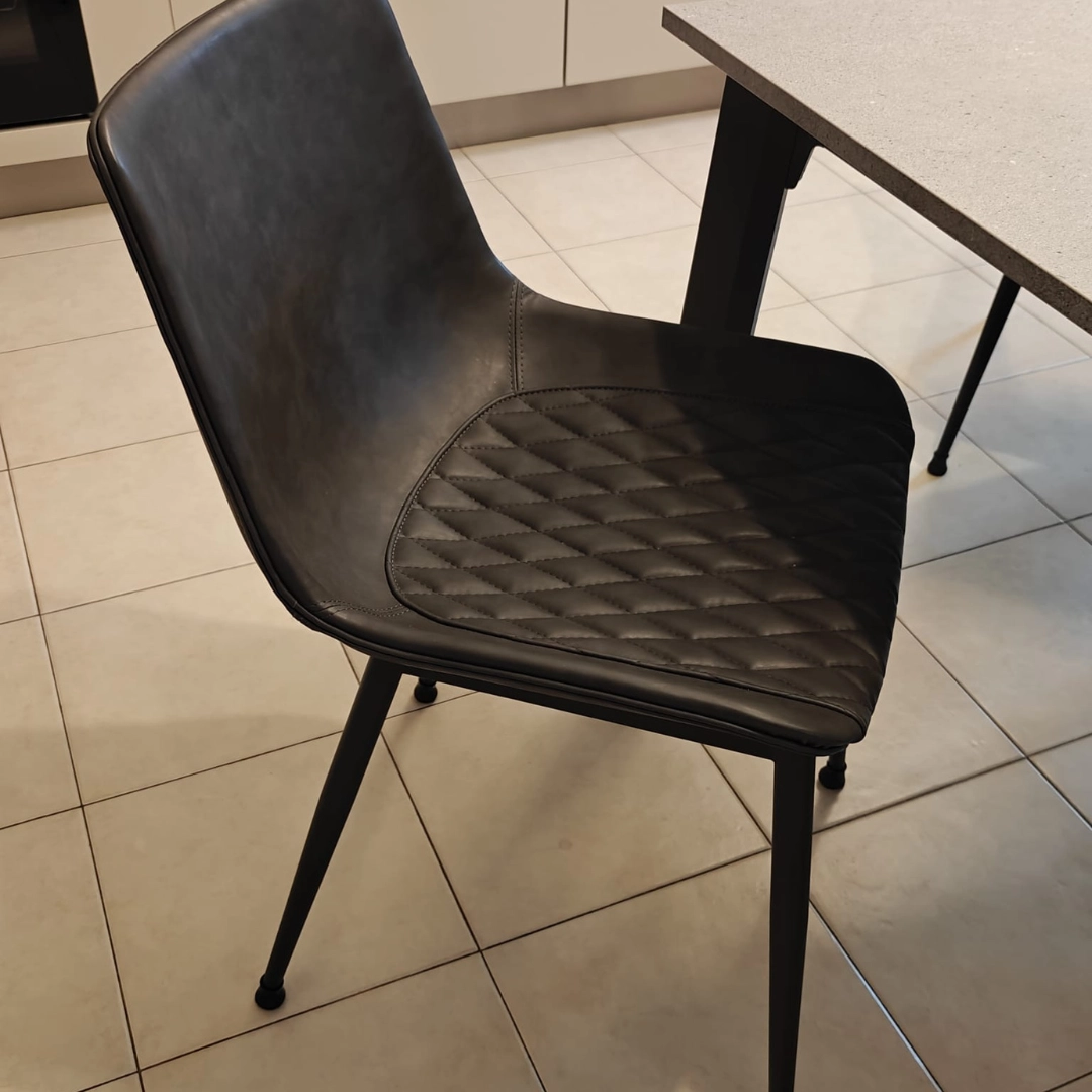 Dettaglio laterale sedia moderna in ecopelle colore antracite accostata al tavolo - Marca Design Shop