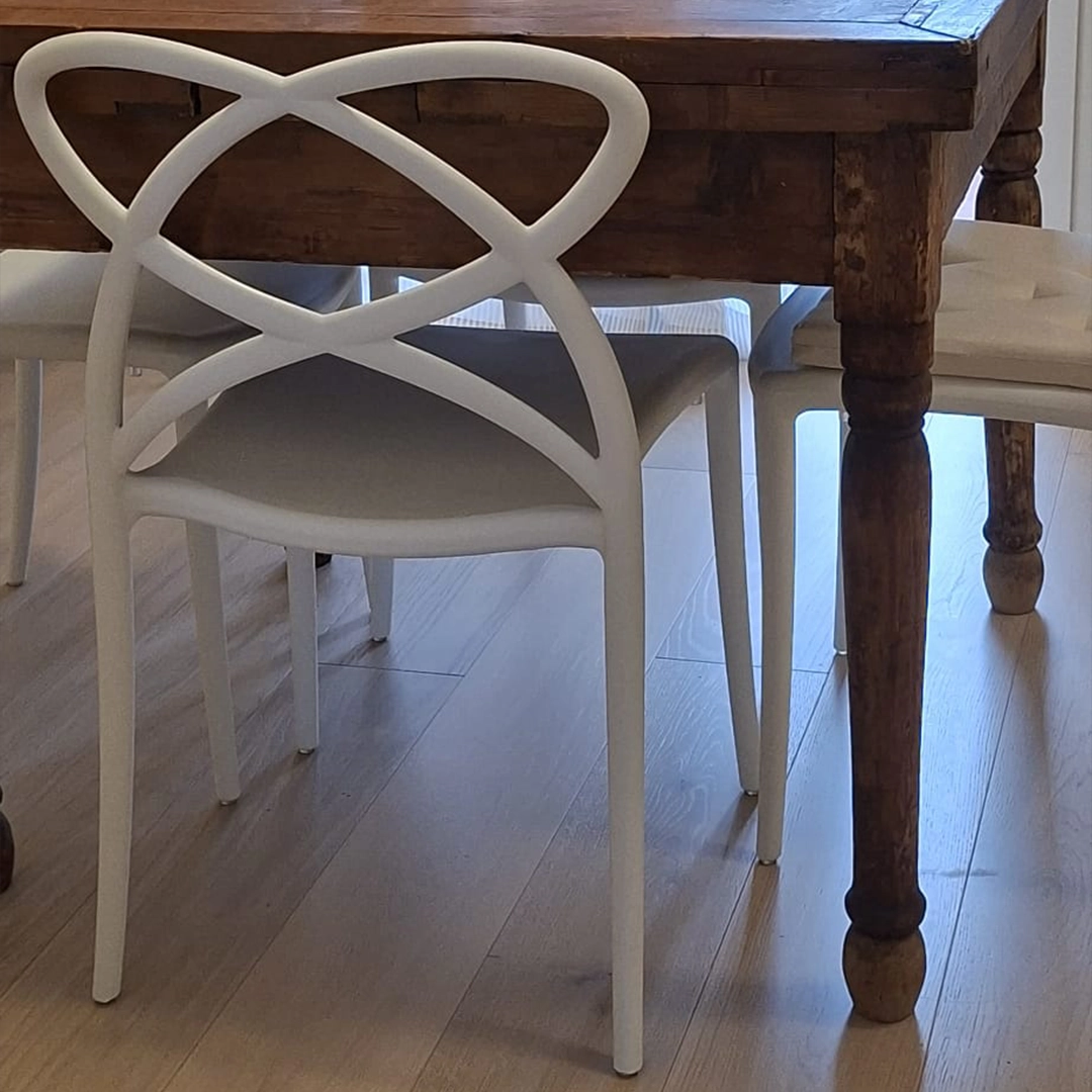 Primo piano dello schienale dal design intrecciato di una sedia moderna impilabile in polipropilene bianco del set da 4 pezzi.