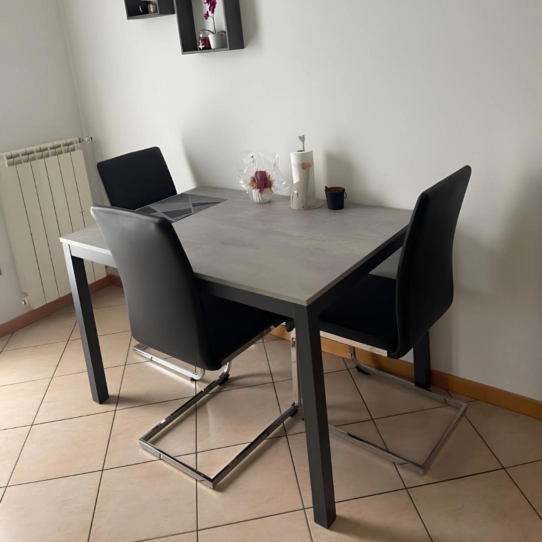 Tavolo rettangolare moderno con piano effetto cemento grigio e struttura in metallo antracite in versione chiusa