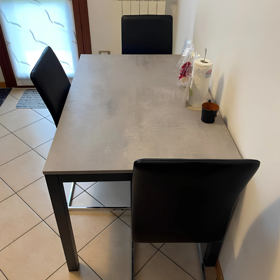 Tavolo da pranzo allungabile finitura effetto cemento con sedia nera abbinata visto dall'alto