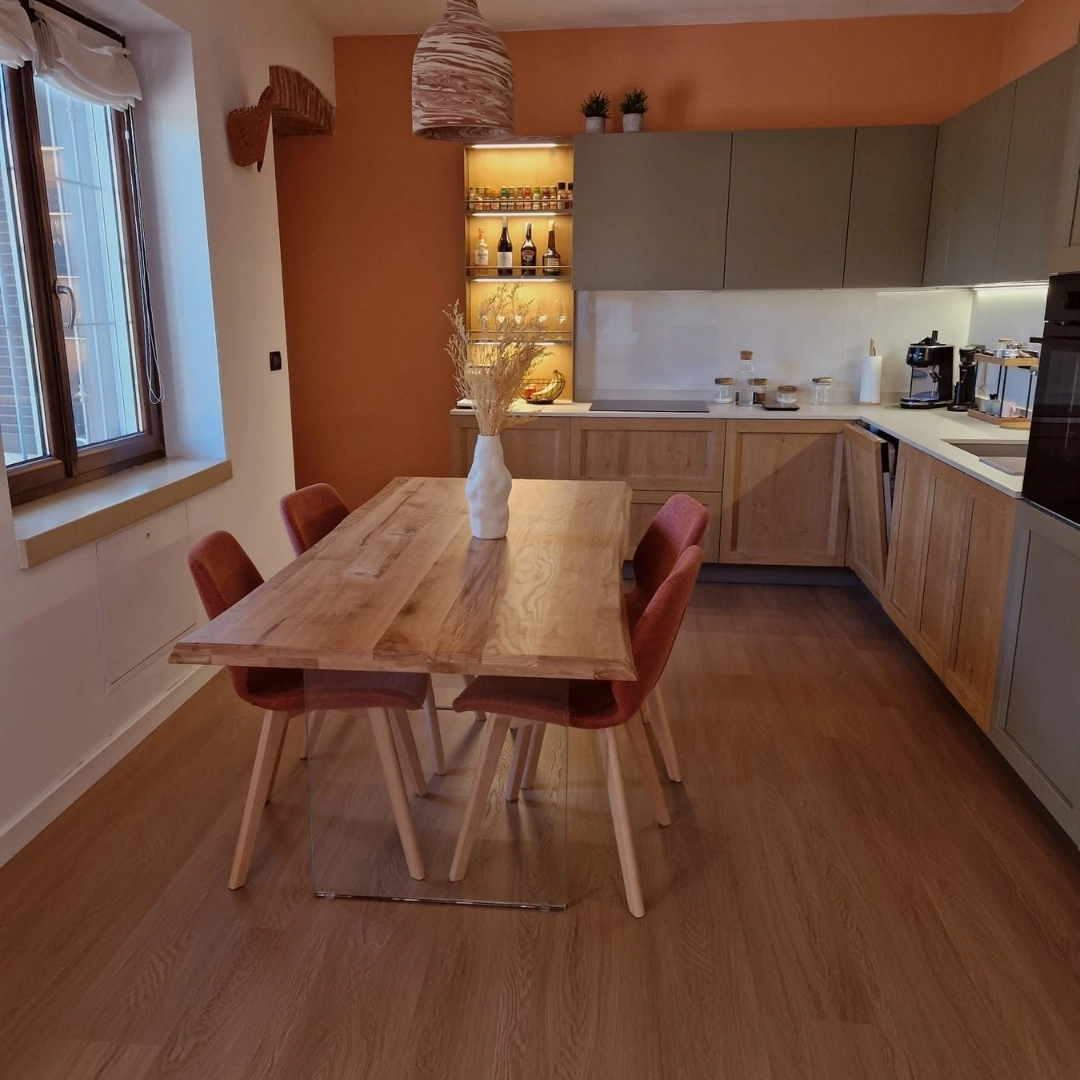 Soggiorno moderno open space con cucina bicolore, tavolo in rovere massello e sedie in tessuto color ruggine