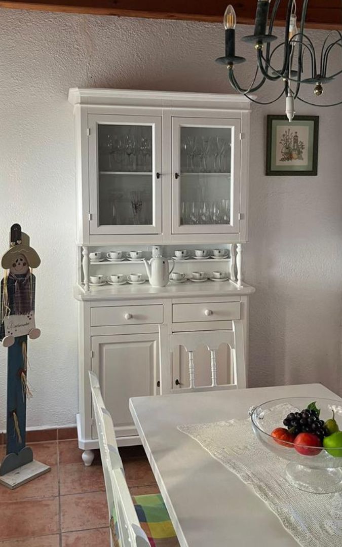 Vetrina in legno bianco opaco posizionata in sala da pranzo con set di tazze.