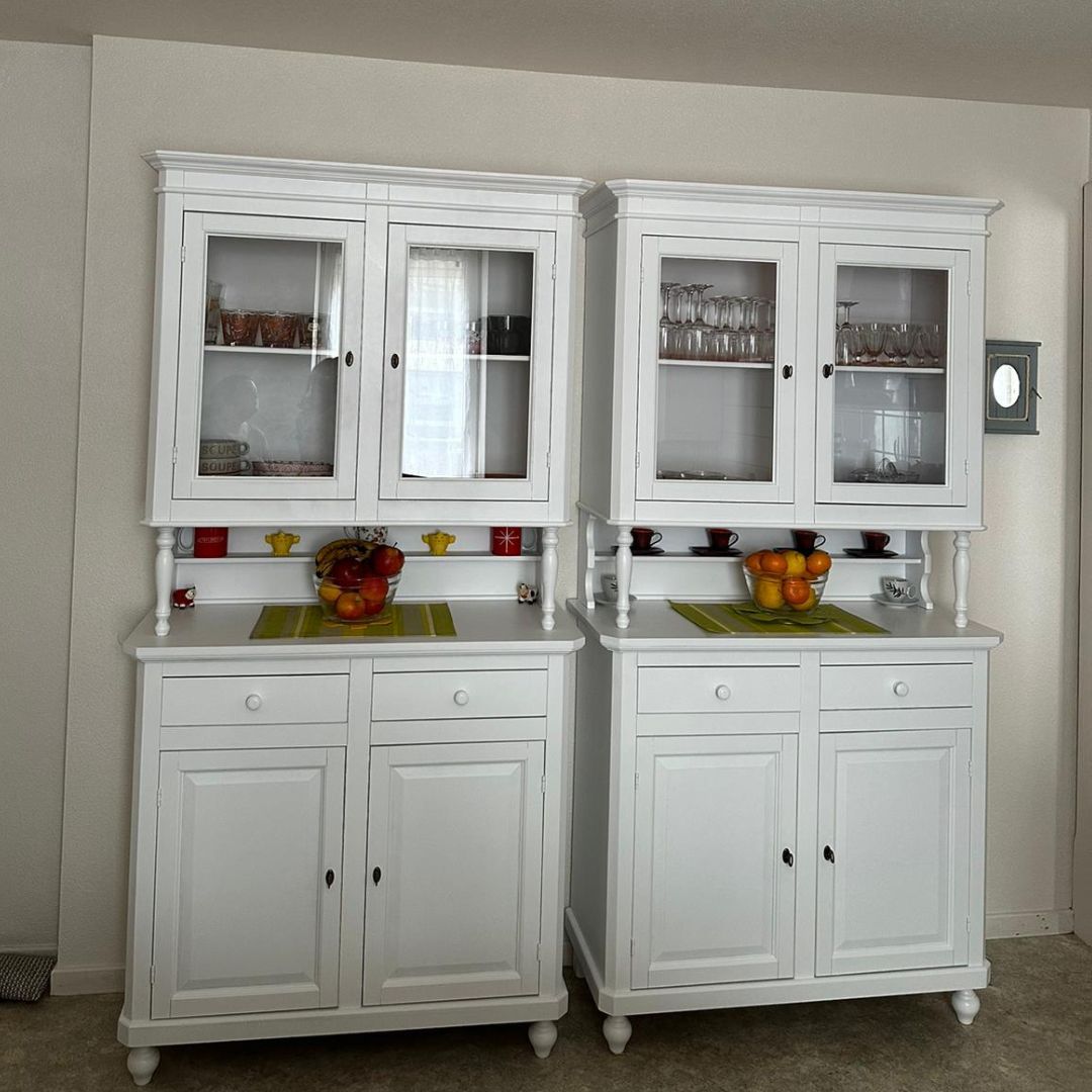 Due vetrine coordinate in legno bianco opaco posizionate in ambiente domestico.
